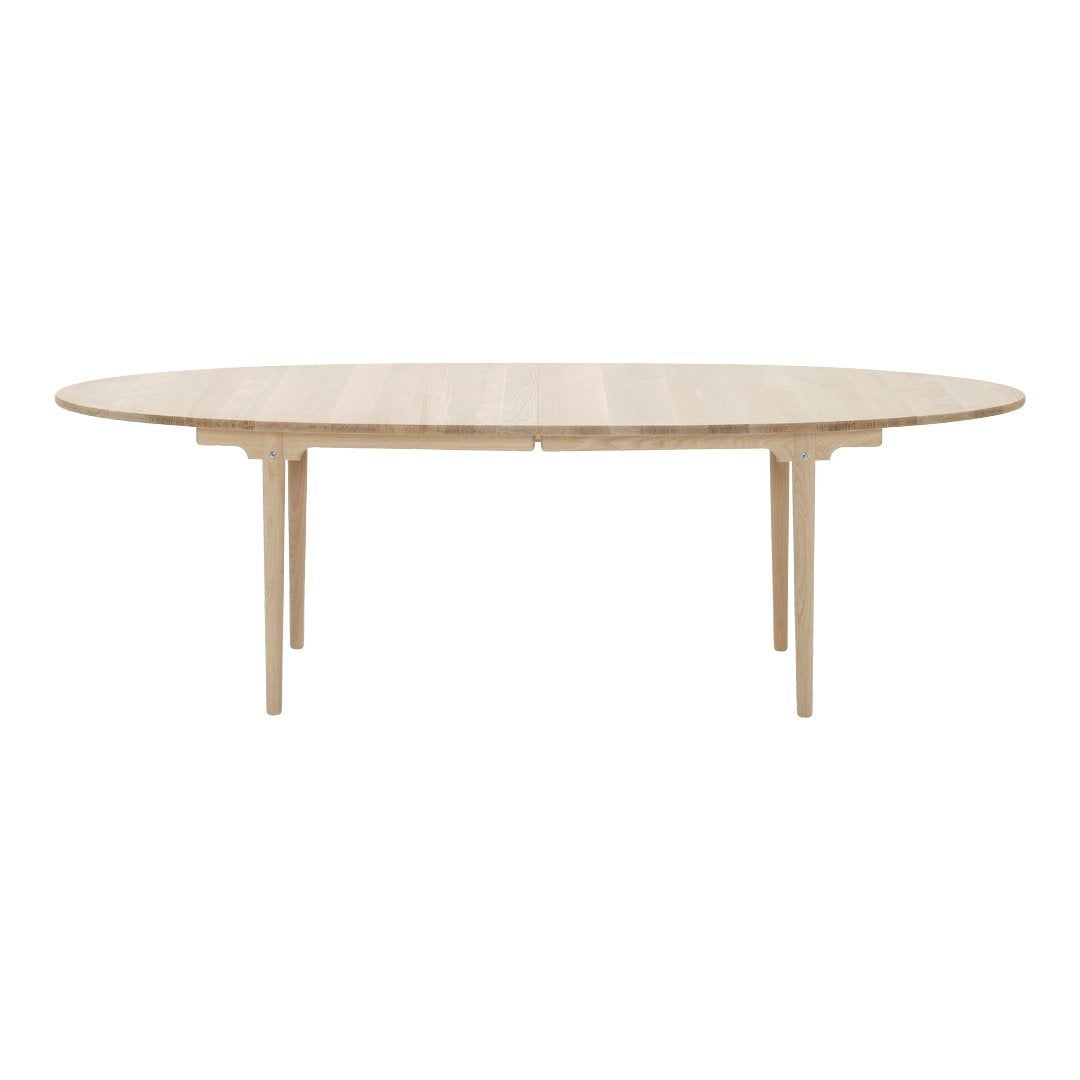 Light wood oval dining table with a smooth finish and minimalist design, showcasing natural wood grain patterns.