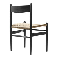 Black wooden chair with a natural woven seat, showcasing a minimalist design and neutral color palette.
