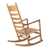 Natural wood rocking chair with a light oak finish and a simple, slatted design. Features a woven seat for comfort.