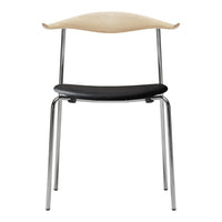 Stylish chair with a light wood backrest, black seat, and sleek chrome legs. Modern and minimalist design.
