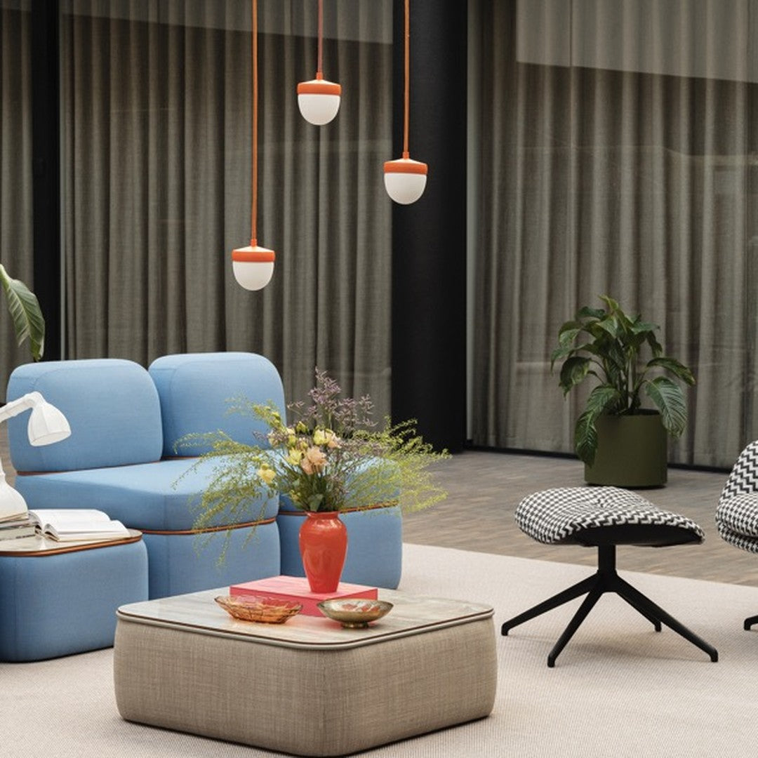 Blue sofa with orange accents, patterned chairs, green plant, and beige table set against soft beige and gray tones.