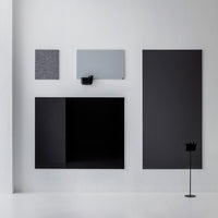 Elegant wall display featuring black, gray, and patterned panels in various shapes against a minimalist white background.