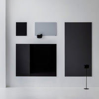 Abstract wall art display featuring a mix of black and gray panels in varying sizes and sleek, modern designs.