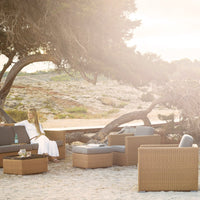 Coastal outdoor furniture set featuring gray cushions and woven brown rattan, perfect for beachside relaxation.
