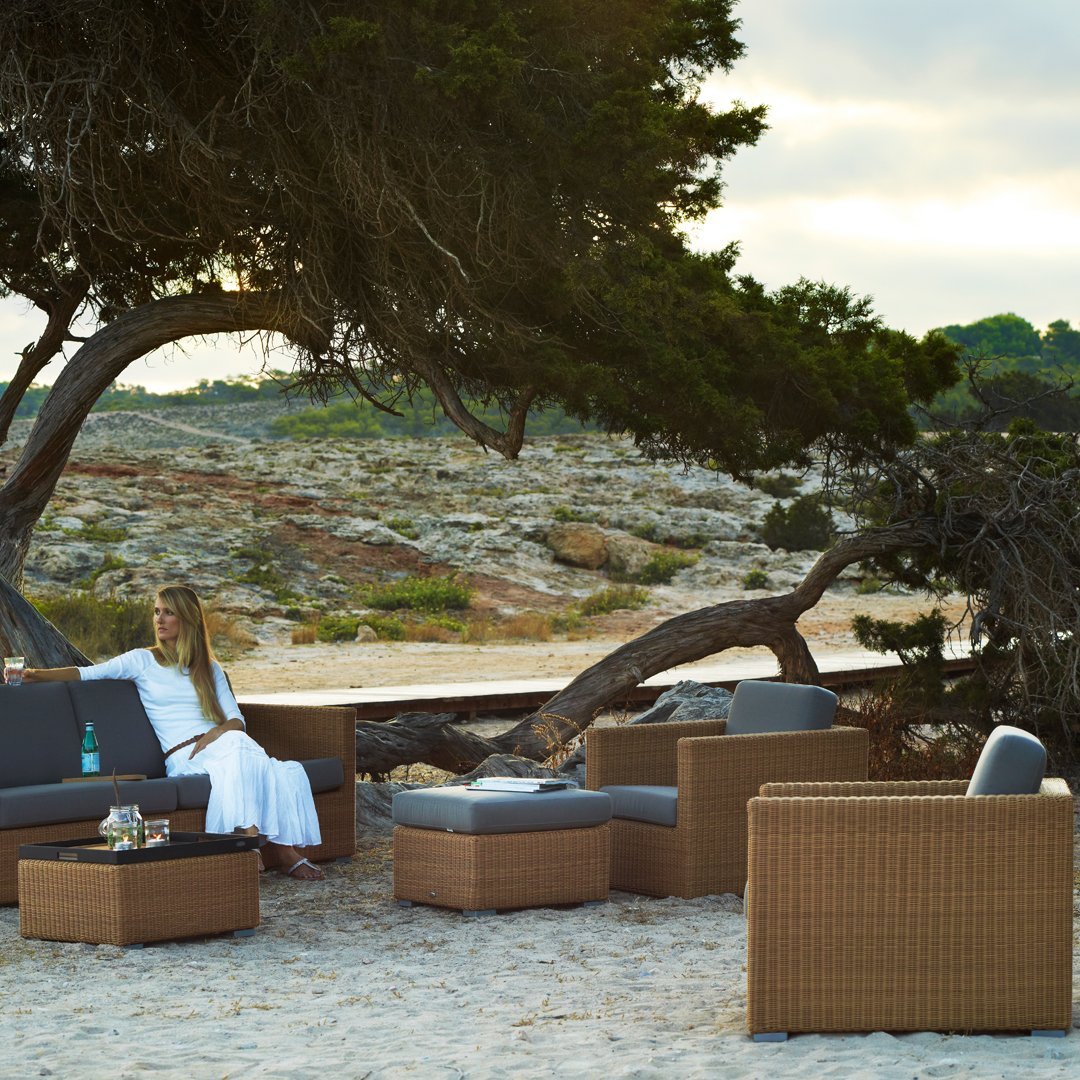 Stylish outdoor furniture set with gray cushions and woven brown accents, perfect for beachside relaxation.