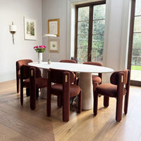 Brown upholstered chairs surround a white oval table, set on warm wood flooring, in a stylish interior.