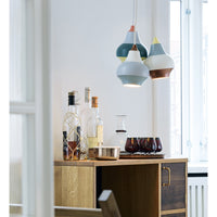 Colorful pendant lamps in shades of blue, green, cream, and terracotta with geometric patterns, stylishly arranged over a wooden table.
