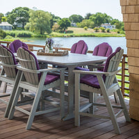 Gray outdoor table with purple cushioned chairs, set against a scenic lakeside view.