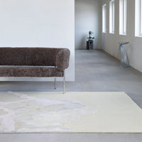 "Neutral cream area rug with subtle abstract gray pattern, complementing modern interior decor."