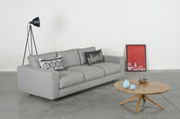 Gray modern sofa with geometric patterned cushions and a warm wooden coffee table, accented by turquoise decor.