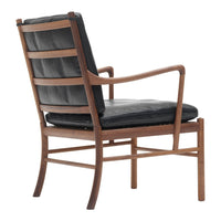 Black leather upholstered chair with a wooden frame and sleek, horizontal slat detailing. Modern design in dark tones.