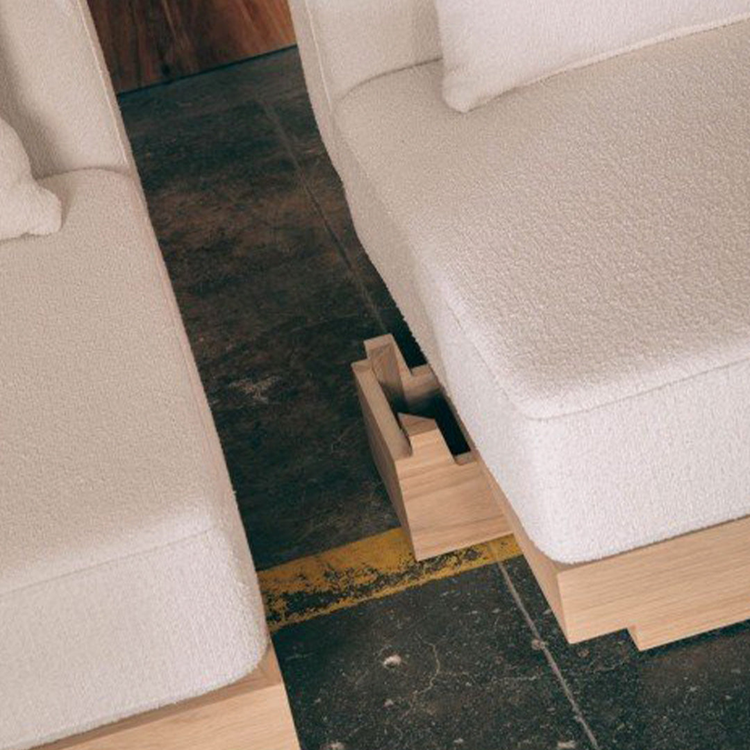 White textured upholstery on modern sofa sections with natural wood accents, set against a minimalist background.