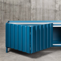 Blue ribbed corner cabinet with a sleek design, featuring a contemporary finish and contrasting white accents.