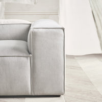Light gray sofa with smooth fabric and minimalist design, featuring clean lines and subtle texture. Perfect for modern decor.