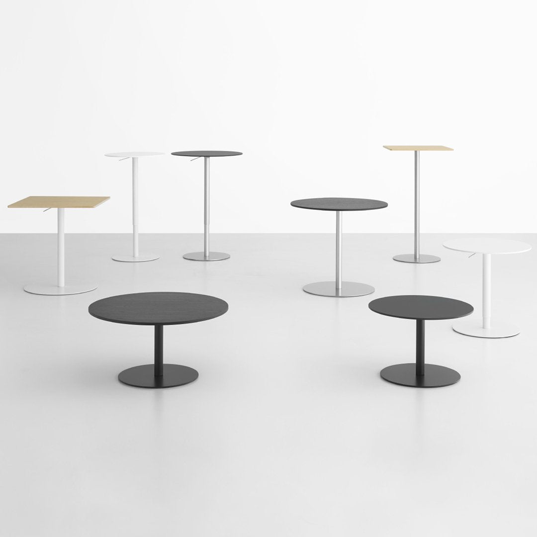 Various modern tables in black, white, and wood finishes, showcasing minimalist designs and round/square shapes.