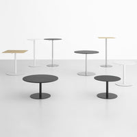 Various modern tables in black, white, and wood finishes, showcasing minimalist designs and round/square shapes.