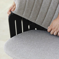 Gray and white striped fabric cushion being adjusted on a black wooden chair.