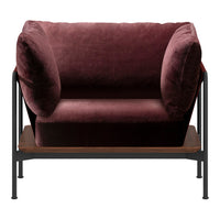 Plush burgundy velvet loveseat with rounded armrests and minimalistic black metal frame, featuring a wood shelf below.