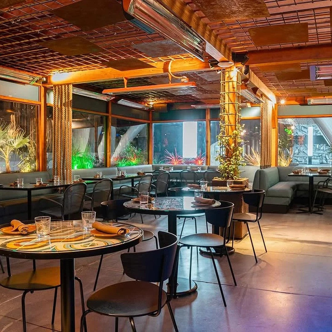 "Modern restaurant interior featuring warm wood tones, sleek black furniture, and vibrant green plant accents."