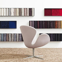 "Curved light pink chair against a backdrop of colorful fabric swatches in various textures and hues."