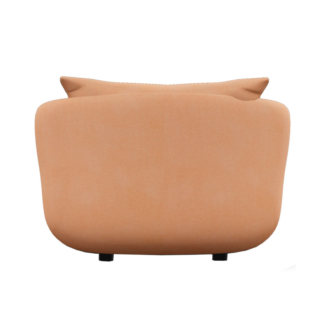Soft peach couch with smooth fabric and minimalistic design, featuring subtle curves and a neutral tone.
