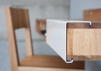 Modern wooden desk with a white drawer and natural wood grain patterns, featuring a sleek, minimalist design.