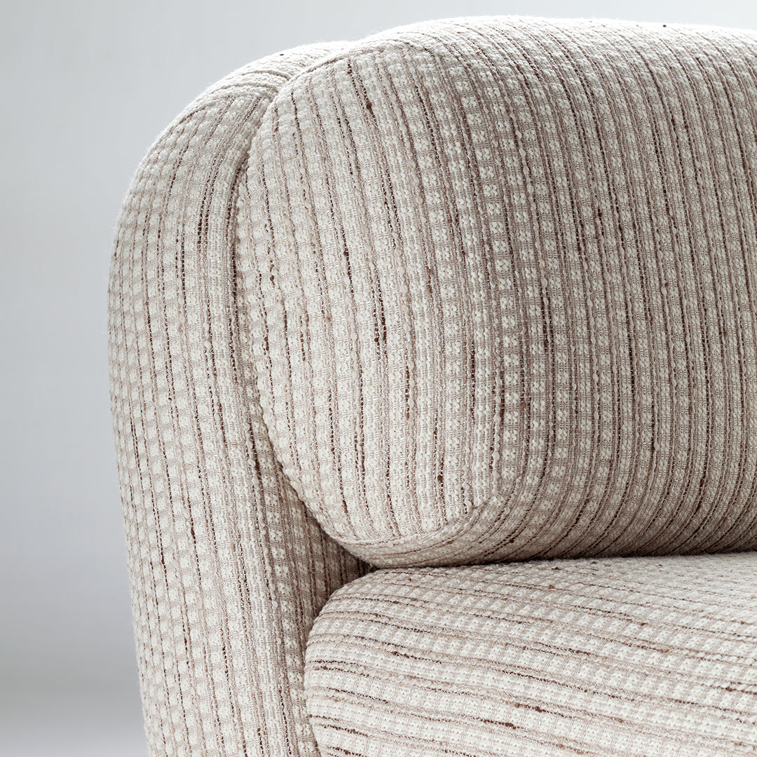 Textured cream fabric with subtle brown stripes, creating a soft, inviting pattern on a modern couch.