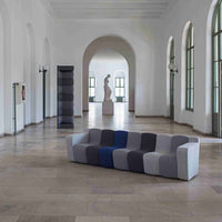 Modern sofa featuring a bold striped pattern in gray, navy blue, and white, set against a minimalist interior backdrop.