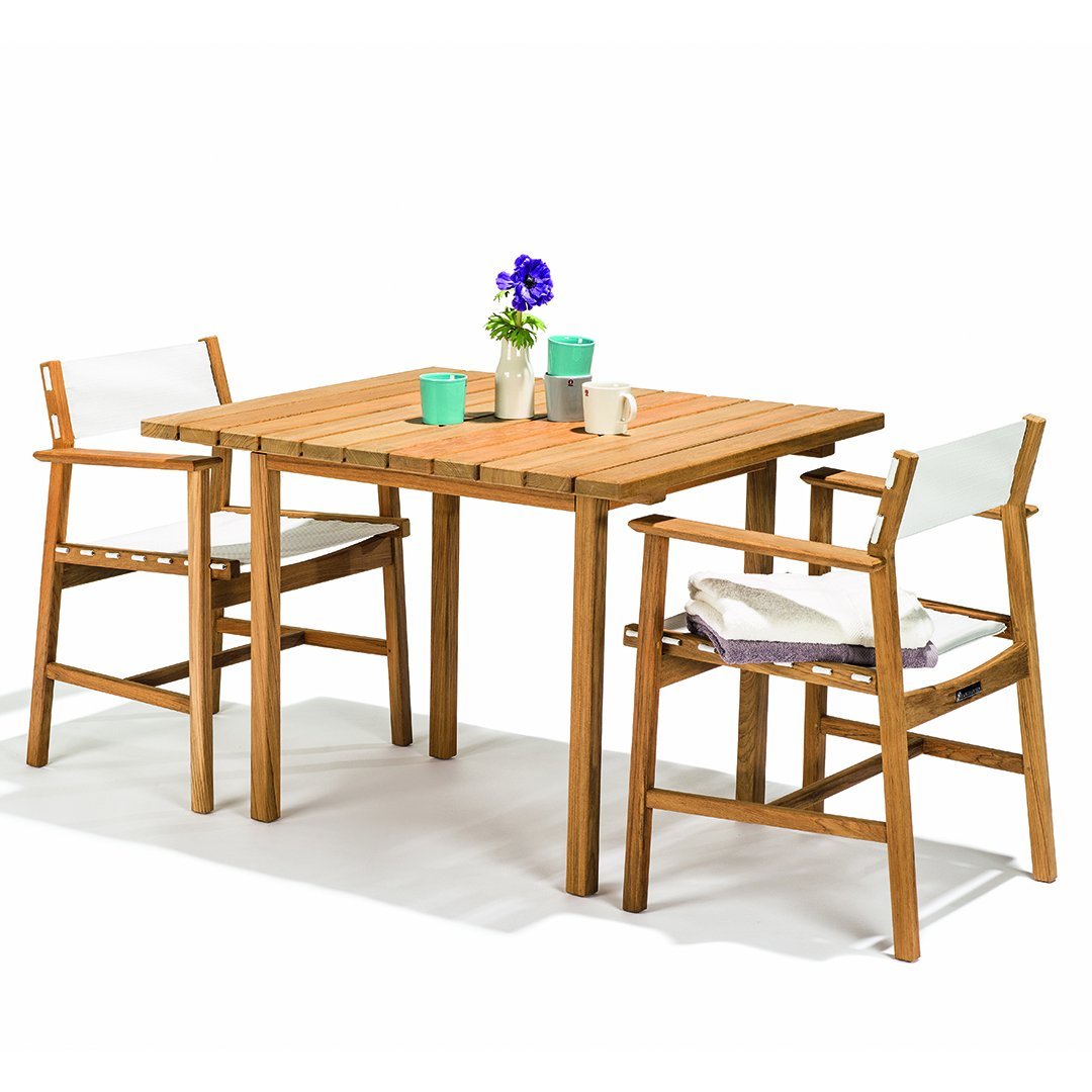 "Natural wood square table with white and light blue accents, complemented by floral decor and patterned chair cushions."