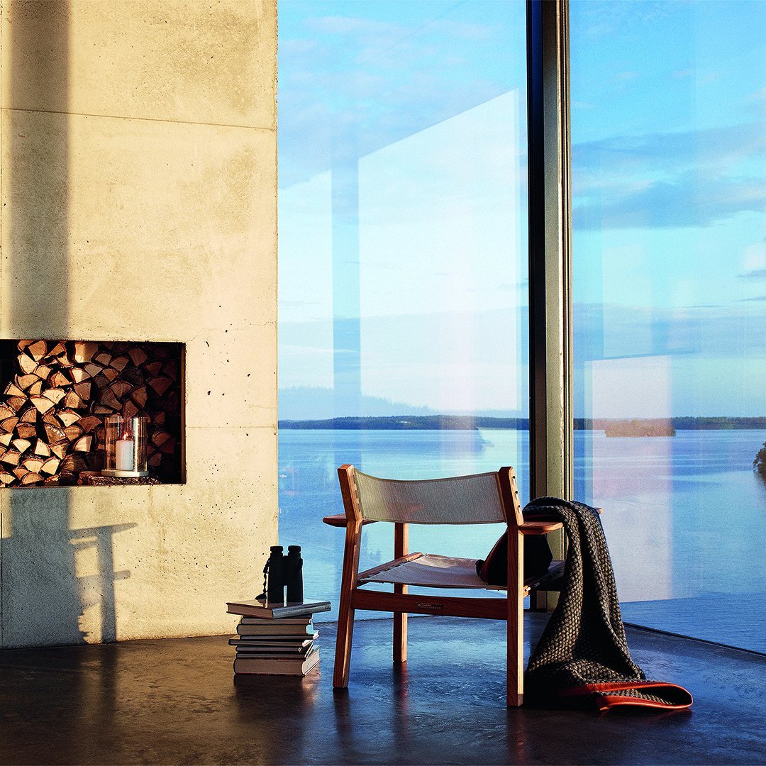 Modern chair with a white seat and wooden frame, set against a backdrop of concrete and a serene blue view.