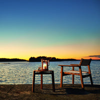 Wooden chairs in warm brown tones against a colorful sunset backdrop with vibrant orange, blue, and purple hues.