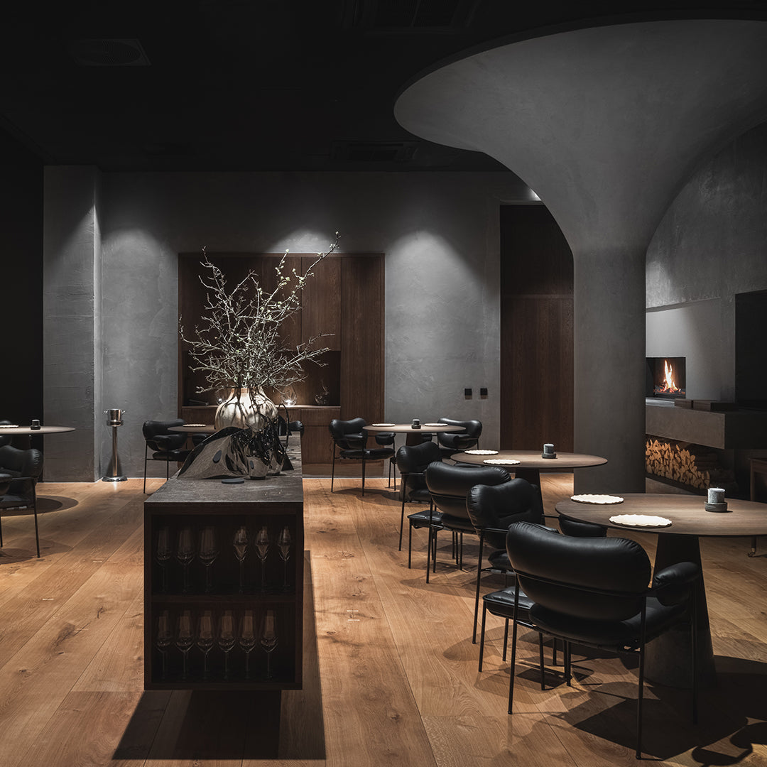 Stylish interior featuring dark gray walls, wooden flooring, and black chairs for a modern aesthetic.
