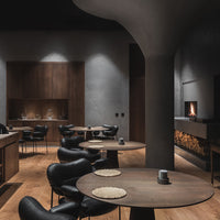 Modern dining space with dark wood accents, black leather chairs, and minimalist decor. Warm wood flooring complements the design.
