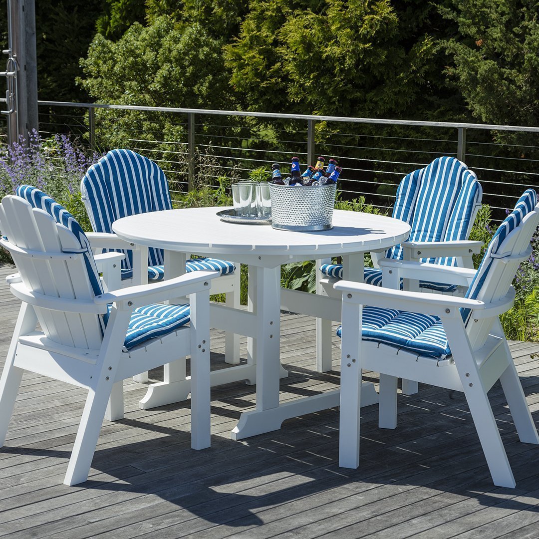Blue and white striped cushions on a white outdoor dining set with a round table and chairs.