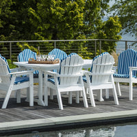 White outdoor furniture with blue and white striped cushions, set on a wooden deck by a serene water view.