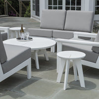 Modern outdoor furniture set featuring white frames with soft gray cushions, circular table, and minimalist design.
