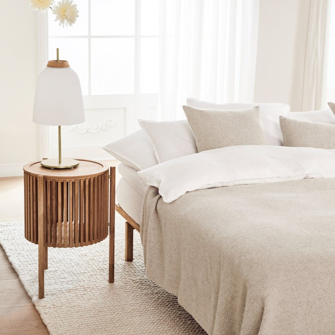 Light beige bedding with textured patterns, complemented by a wooden bedside table and neutral decor accents.