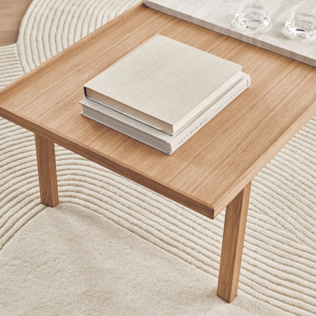 Light oak wood table with a smooth surface, featuring subtle natural grain and stacked neutral-toned books.