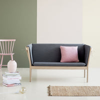Gray sofa with pink accent pillow, set against green and light pastel wall colors, paired with a neutral rug.