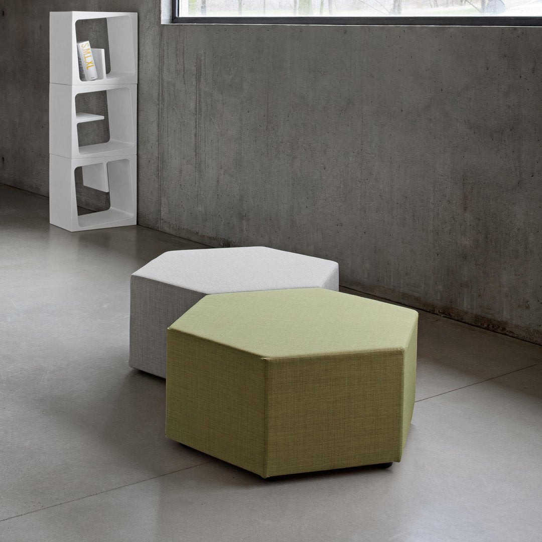 Hexagonal ottomans in muted white and vibrant green fabrics with a textured finish, set on a sleek floor.