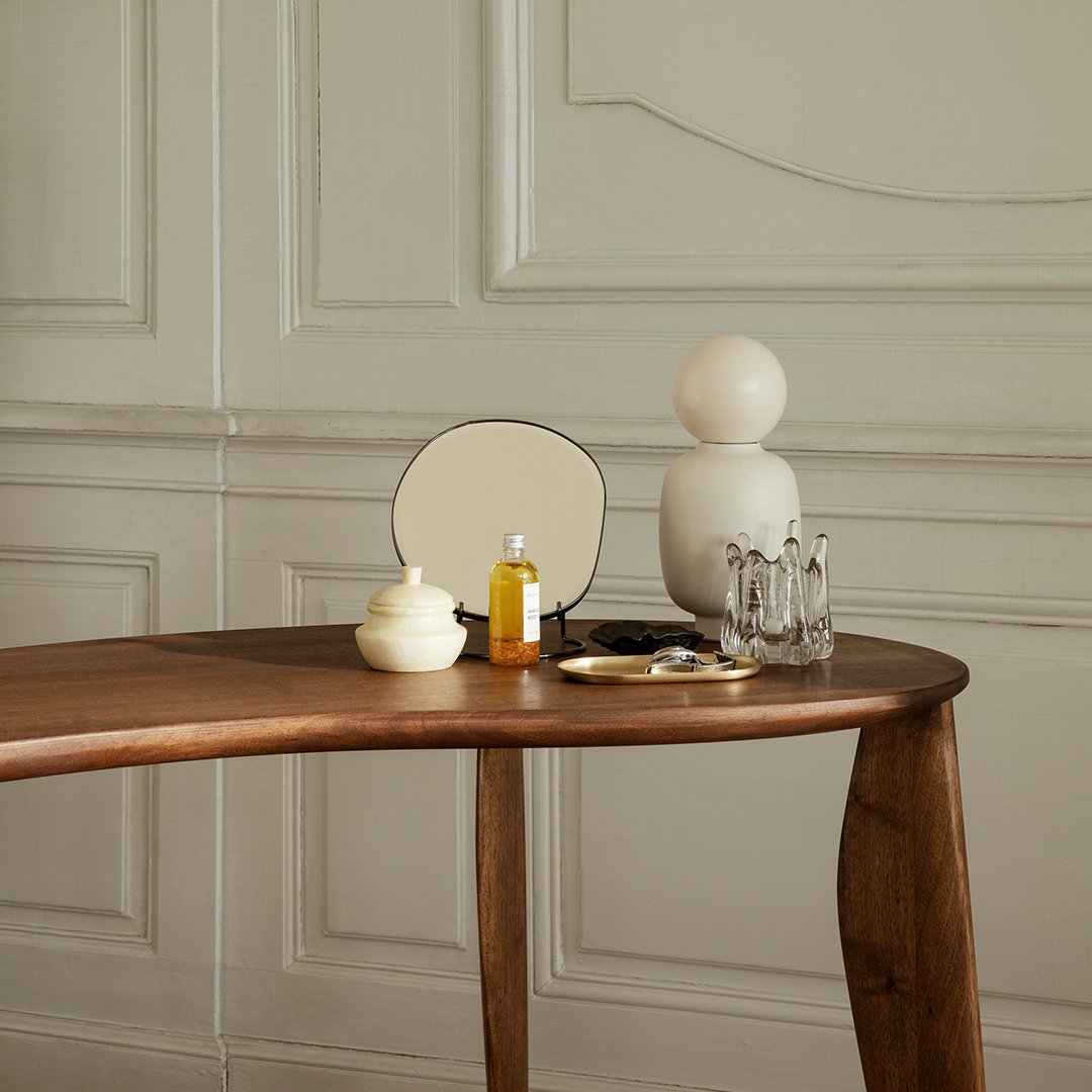 "Minimalist wooden table with neutral tones, cream accents, and smooth, round shapes in a stylish indoor setting."