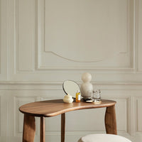 Wooden desk with smooth, curved edges, contrasting light cream and natural wood tones against a soft, neutral background.