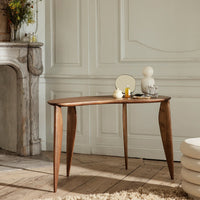 "Curved walnut side table with smooth surface and elegant, tapered legs, set in a bright, neutral room."