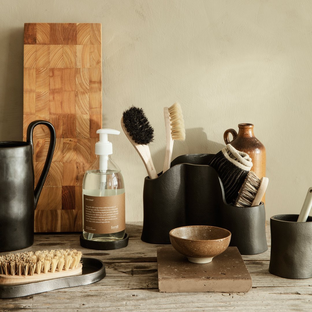 Matte black and earthy brown kitchen utensils and decor arranged on a rustic wooden surface, featuring natural textures.