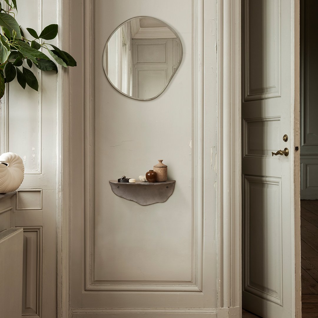 Gray wall shelf with soft curves, reflecting a muted color palette of beige and light gray. Circular mirror adds elegance.