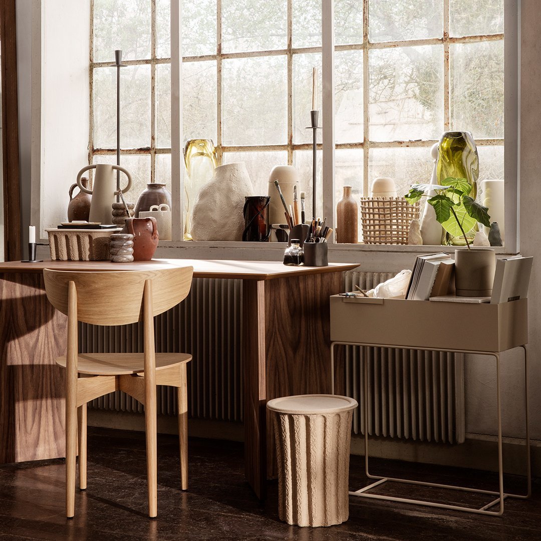Natural wood furniture with neutral tones, soft beige patterns, and green glass accents in a warmly lit workspace.