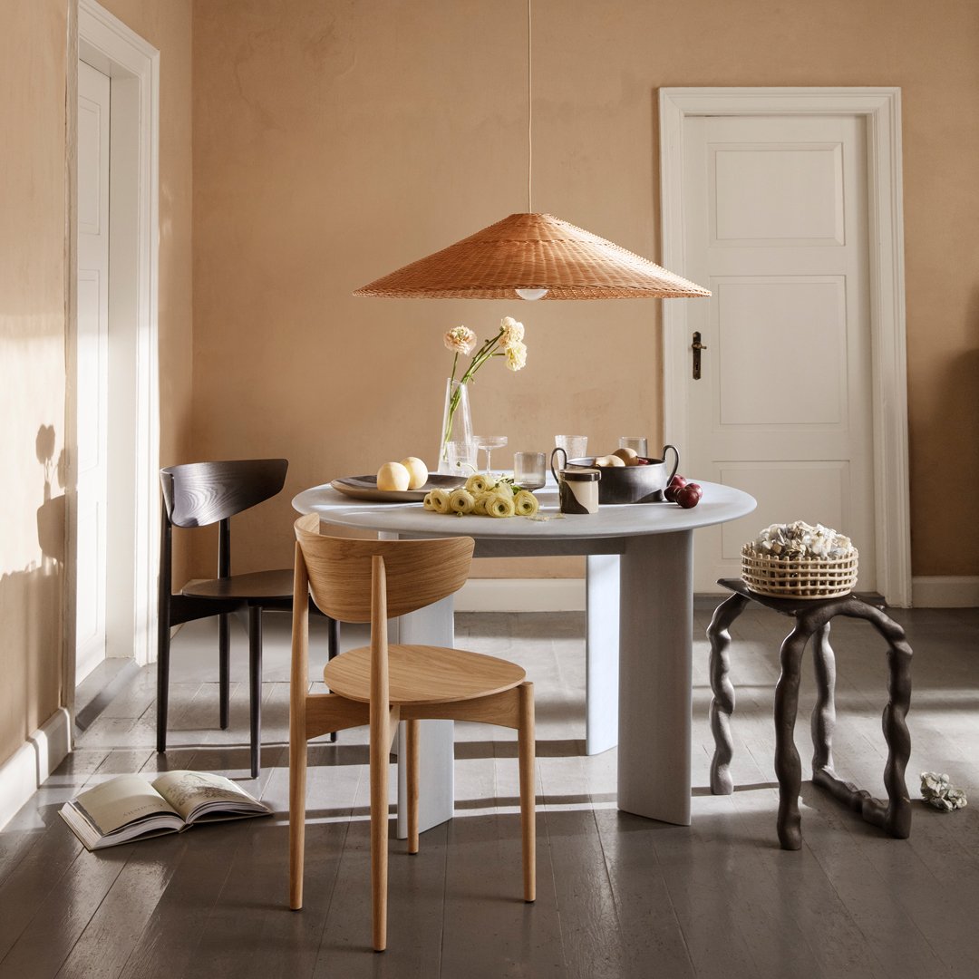 Warm beige walls, natural wood furniture, and a textured woven lampshade create a cozy dining atmosphere.