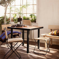 Modern black and wood table with natural-toned chairs, featuring colorful striped cushions and warm, inviting decor.