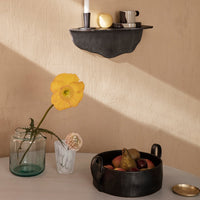 Black wall shelf with smooth edges, yellow flower vase, marble accents, and earthy fruit bowl in soft, neutral tones.