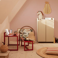 Red accent tables, beige cabinet, soft pink walls, patterned artwork, and textured natural materials create a cozy space.